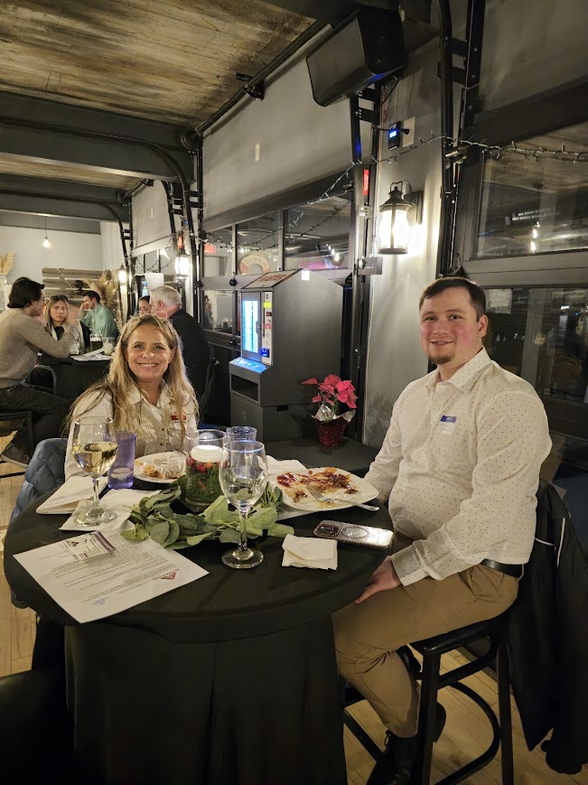 Two attendees at a table with wine and pizza