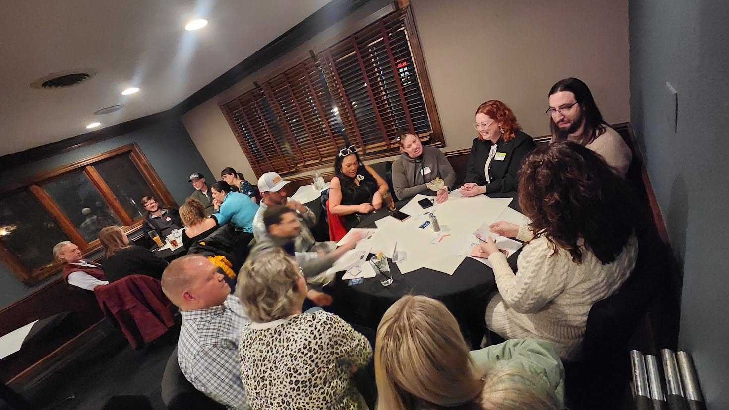 A full room of attendees rotating between tables during speed networking at the Butler Inn